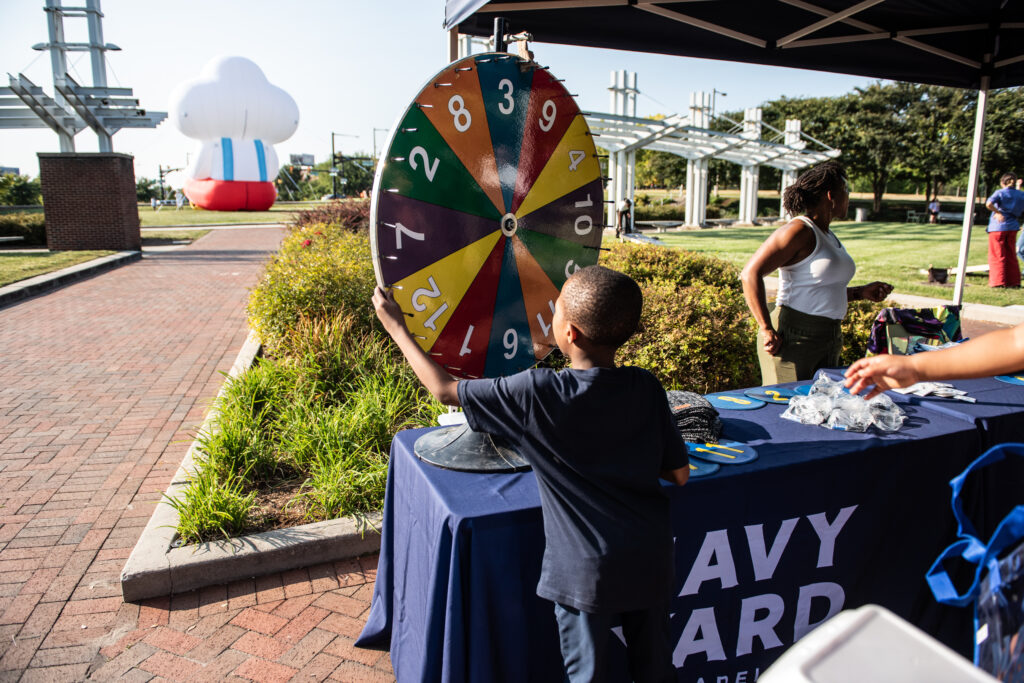 A young boy spins a wheel for a game at a Navy Yard event in Crescent Park.